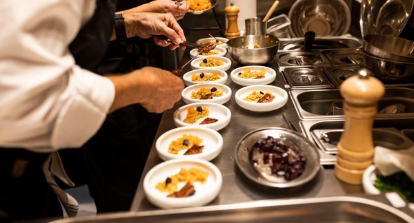 Several people plate and prepare small white dishes that include Aleph Farms cultivated steak in an assembly line.