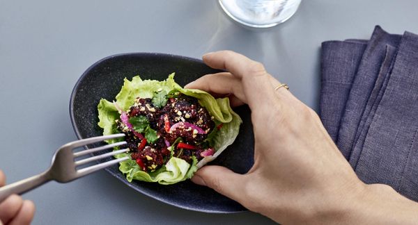 一个人用叉子吃生菜杯里的栽培肉饵沙拉。