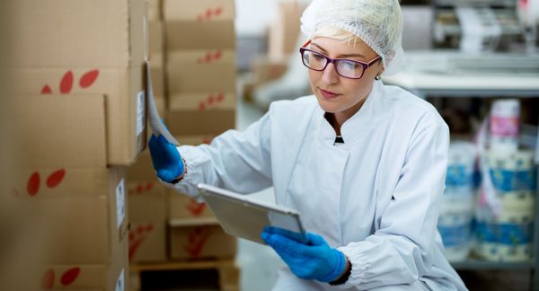 年轻美丽的女工人专注于无菌布使用药片检查纠正库存在工厂储藏室