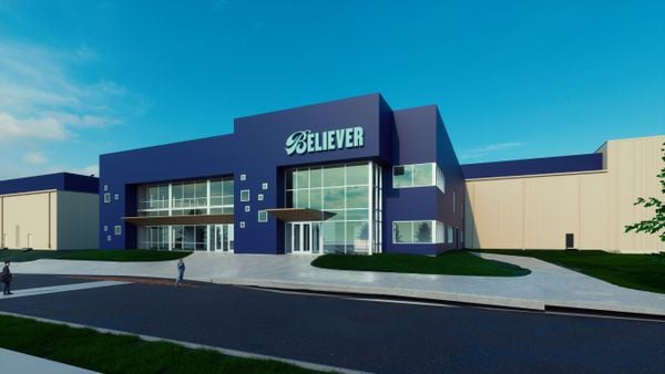 A close up view of a rendering of Believer Meats' commercial facility. The entry portion is navy blue with many windows and Believer's logo. Lower beige wings with navy blue roofs are on the sides.