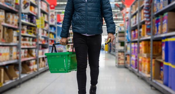 Low angle selected focus view of a person shopping in a supermarket while on a budget.