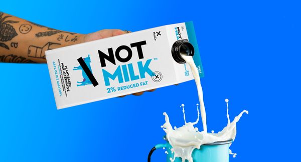 一只手从纸箱中倒入2％的蓝色杯子中。